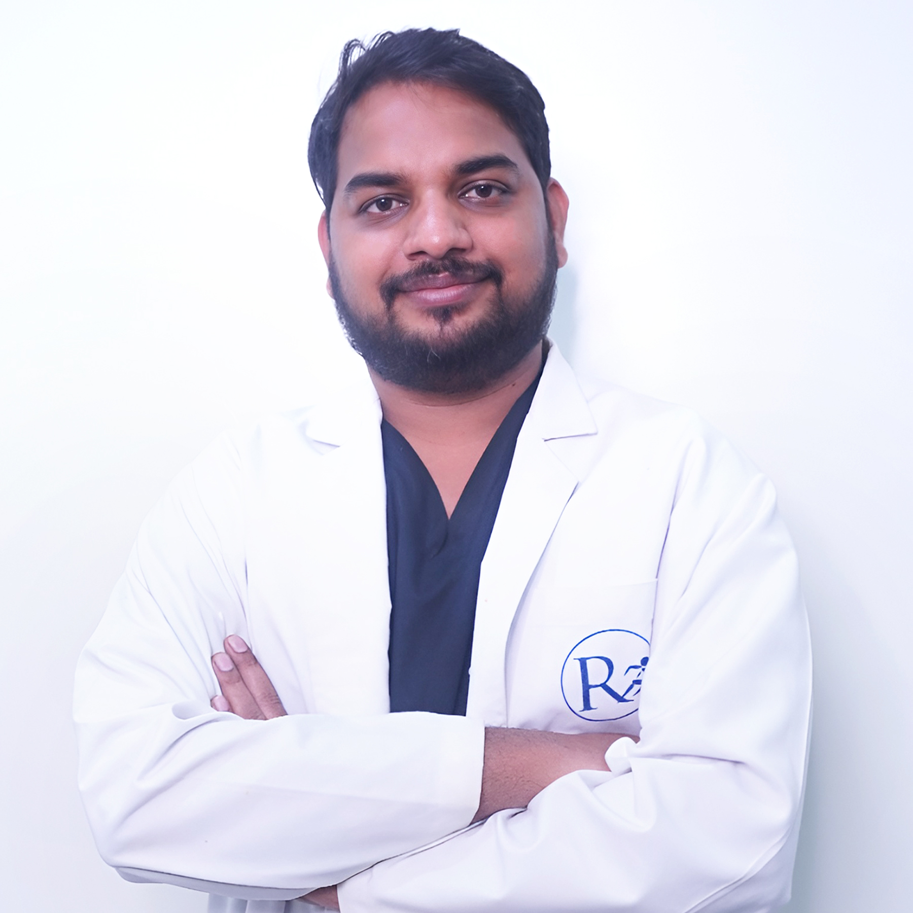Portrait of Dr. Vamshi Krishna, a male general surgeon, smiling and wearing a white coat, vertical rectangle photo